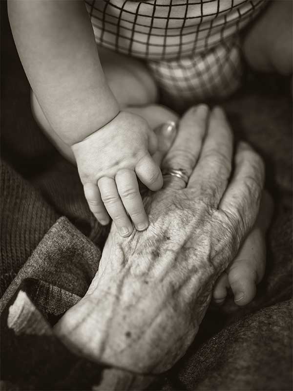 baby hands on top of elder woman hands